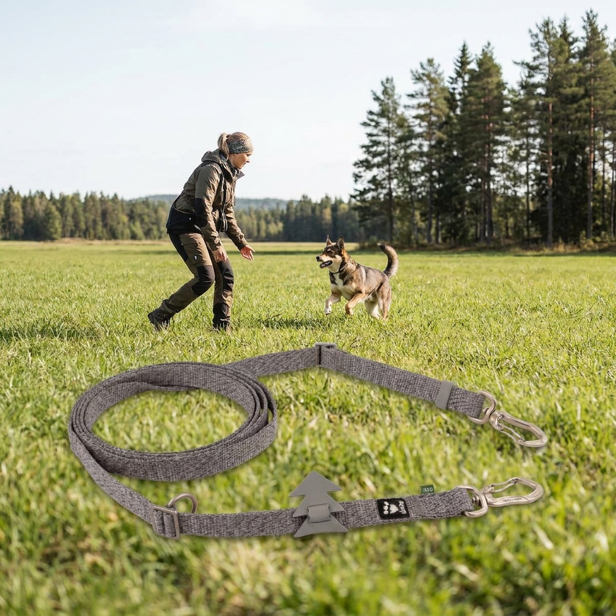Hundtränare som övar inkallning med en lång träningslina på ett grönt skandinaviskt fält