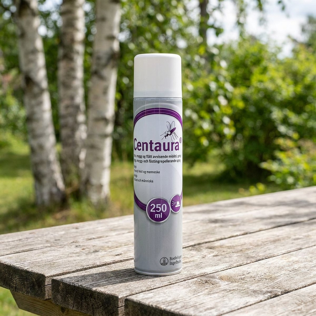 Grå och vit aerosolflaska av Centaura Repellent med lila varumärke stående på ett trädgårdsbord i en skandinavisk trädgård med björkträd i bakgrunden